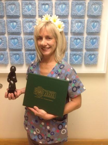 awardee wearing a headband of daisies, daisy award statue, and certificate.