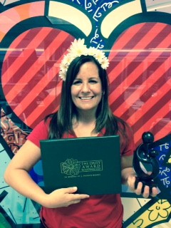 awardee wearing a headband of daisies, daisy award statue, and certificate.